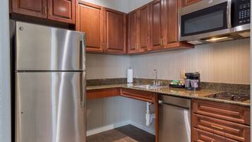 A kitchen with stainless steel appliances, wooden cabinets, granite countertops, and a built-in microwave.