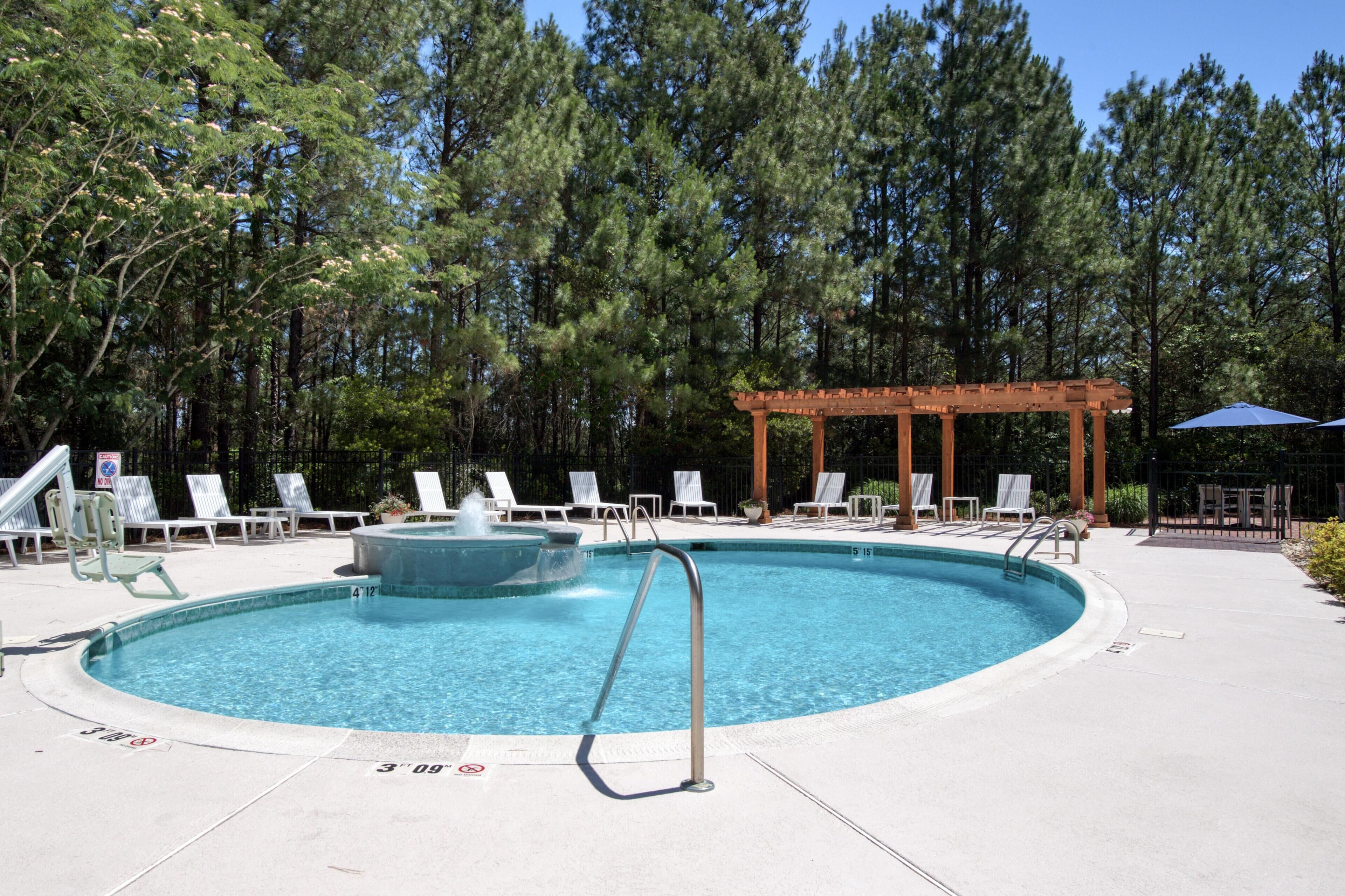 A swimming pool with lounge chairs and a pergola.