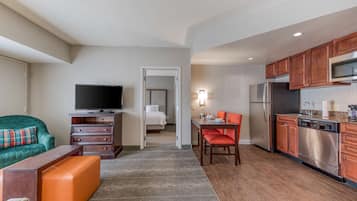 Quarto de hotel moderno com sala de estar, cozinha compacta e quarto separado.