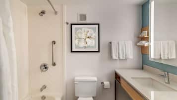 A modern bathroom with a shower, toilet, sink, and a framed floral artwork on the wall.