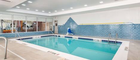 Una piscina interior con carriles claramente delimitados, un muro de azulejos azules e iluminación empotrada en el techo.