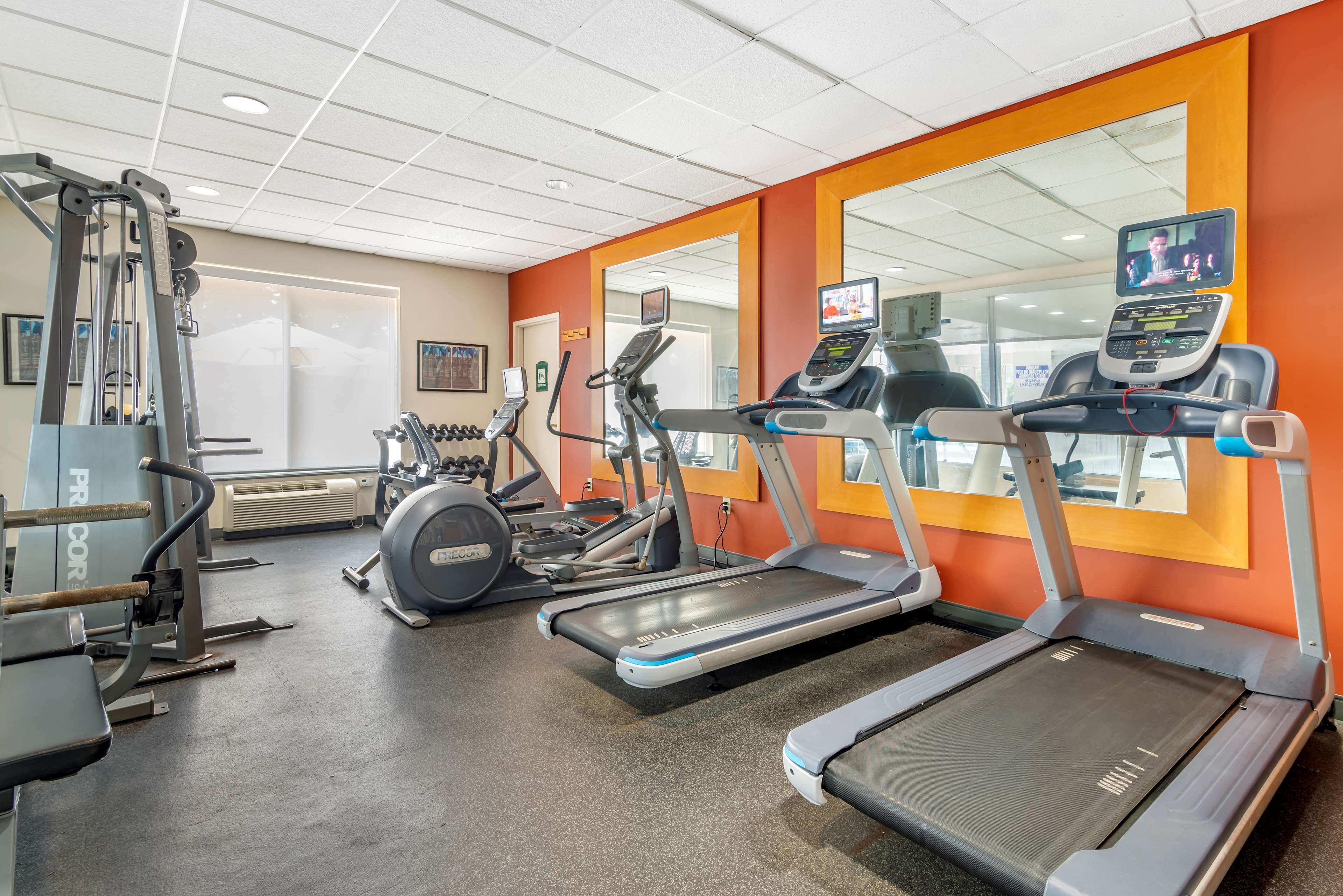A gym with treadmills, a weight machine, and a mirror.