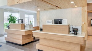A reception desk with a wooden finish, a digital screen, and a printer.