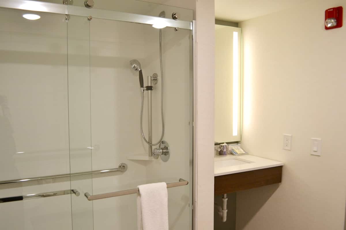 A modern bathroom with a glass-enclosed shower, a wooden vanity, and a mirror above the sink.