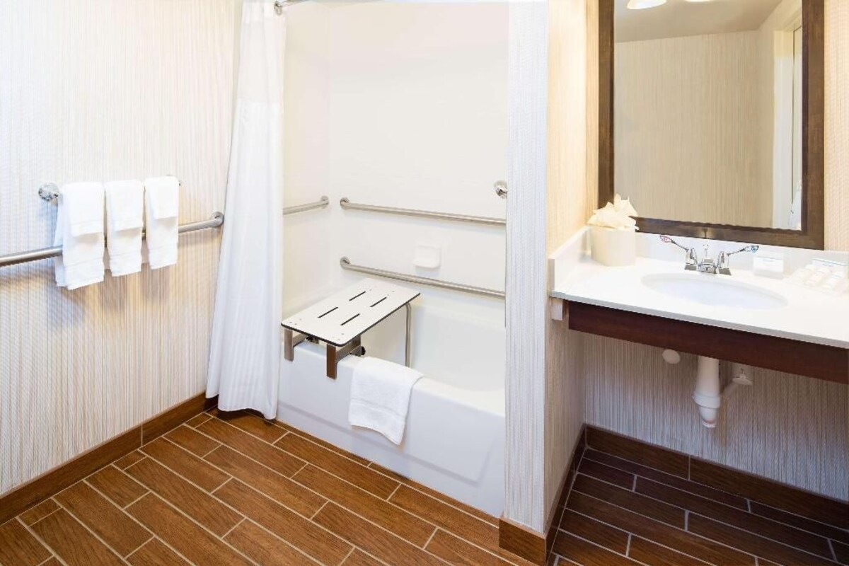 A bathroom with a bathtub, a shower, a sink, and a mirror.