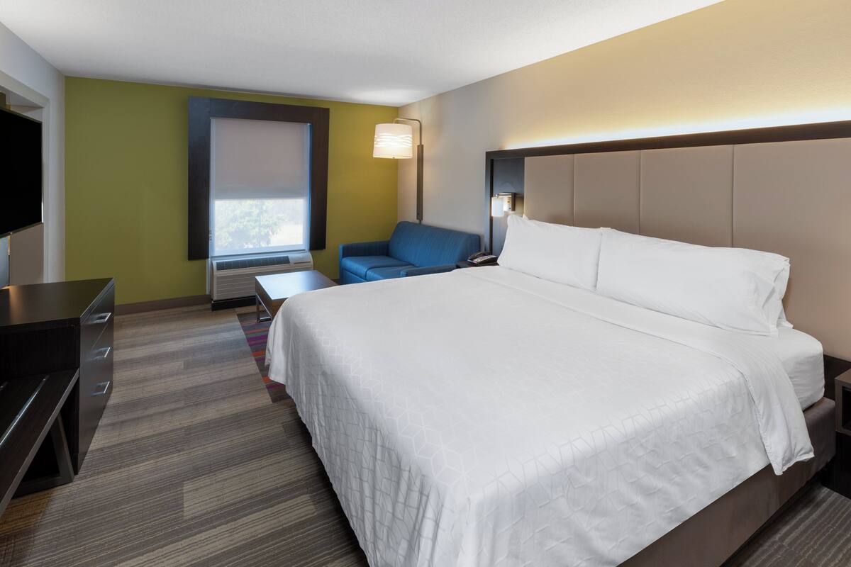 Une chambre d’hôtel avec un grand lit, un bureau, une chaise et un téléviseur.