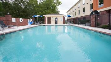 Una piscina al aire libre, sombrillas, sillones reclinables de piscina