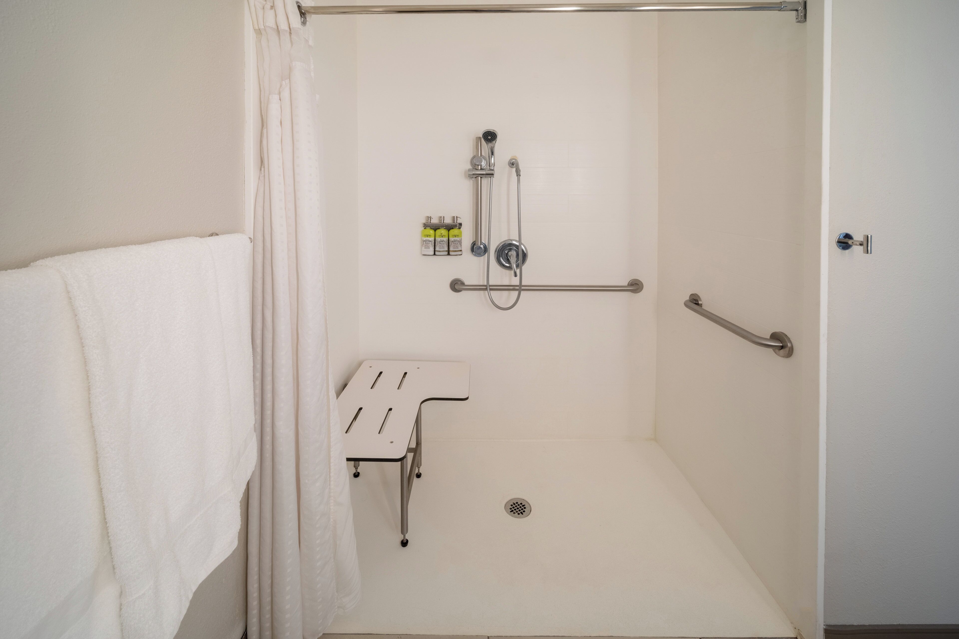 Een douchegedeelte met een handgreep, een handdoekhouder en een klein plankje met toiletartikelen.