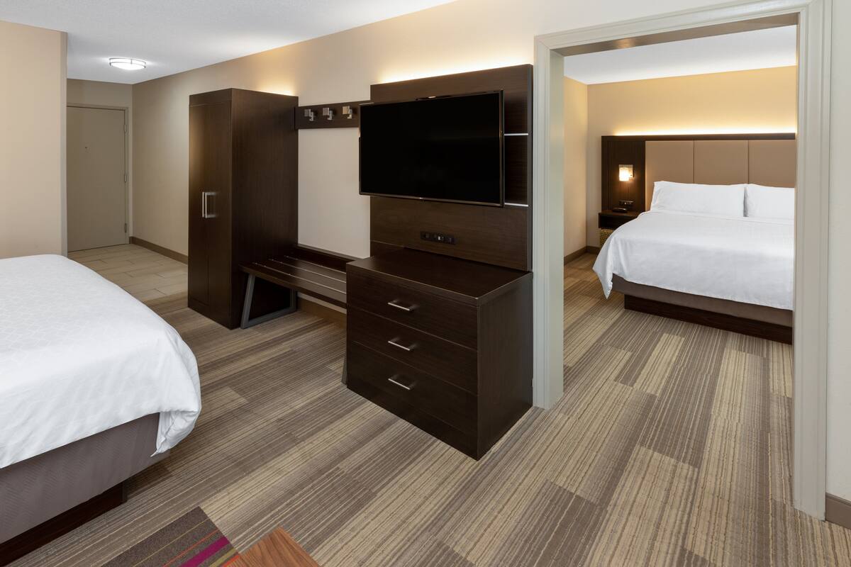 A hotel room with a bed, a TV, a wardrobe, and a desk.