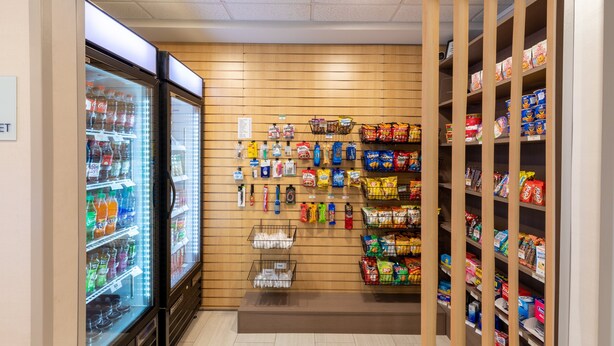 Zona de exhibición de aperitivos con diversos productos envaselados y un dispensador refrigerado para bebidas.