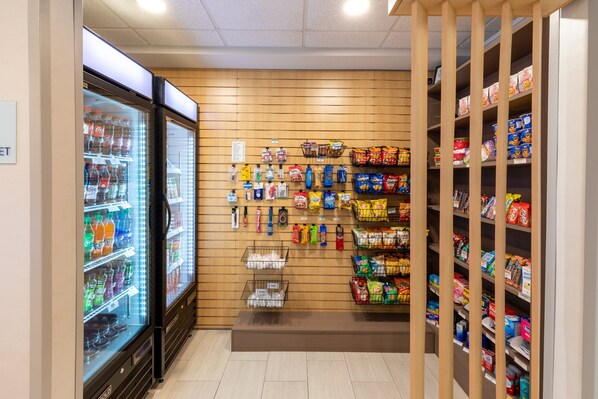 Een ruimte met een snackverkoopwand, diverse verpakte producten en een gekoelde drankdispenser.