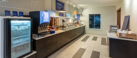 A modern kitchen with a refrigerator, coffee machine, and a breakfast bar.