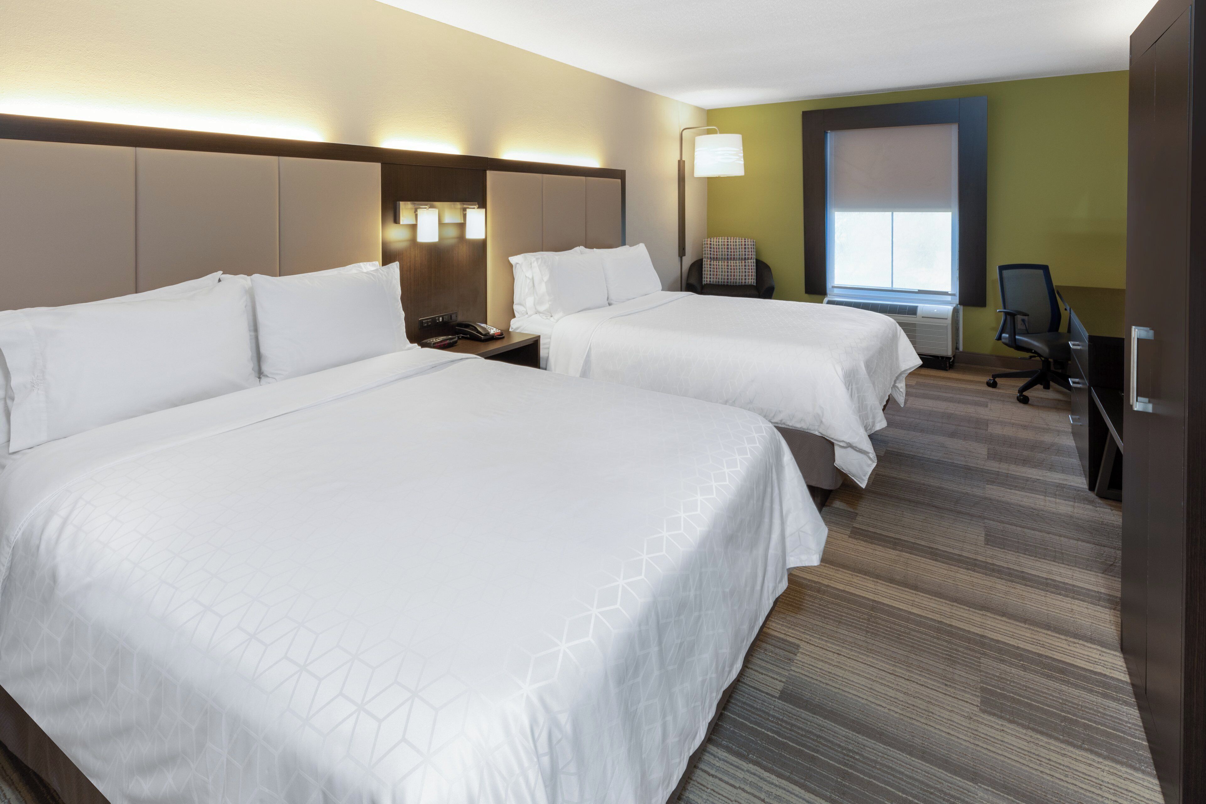 Habitación de hotel con dos camas, un escritorio, una silla, un teléfono y una ventana.