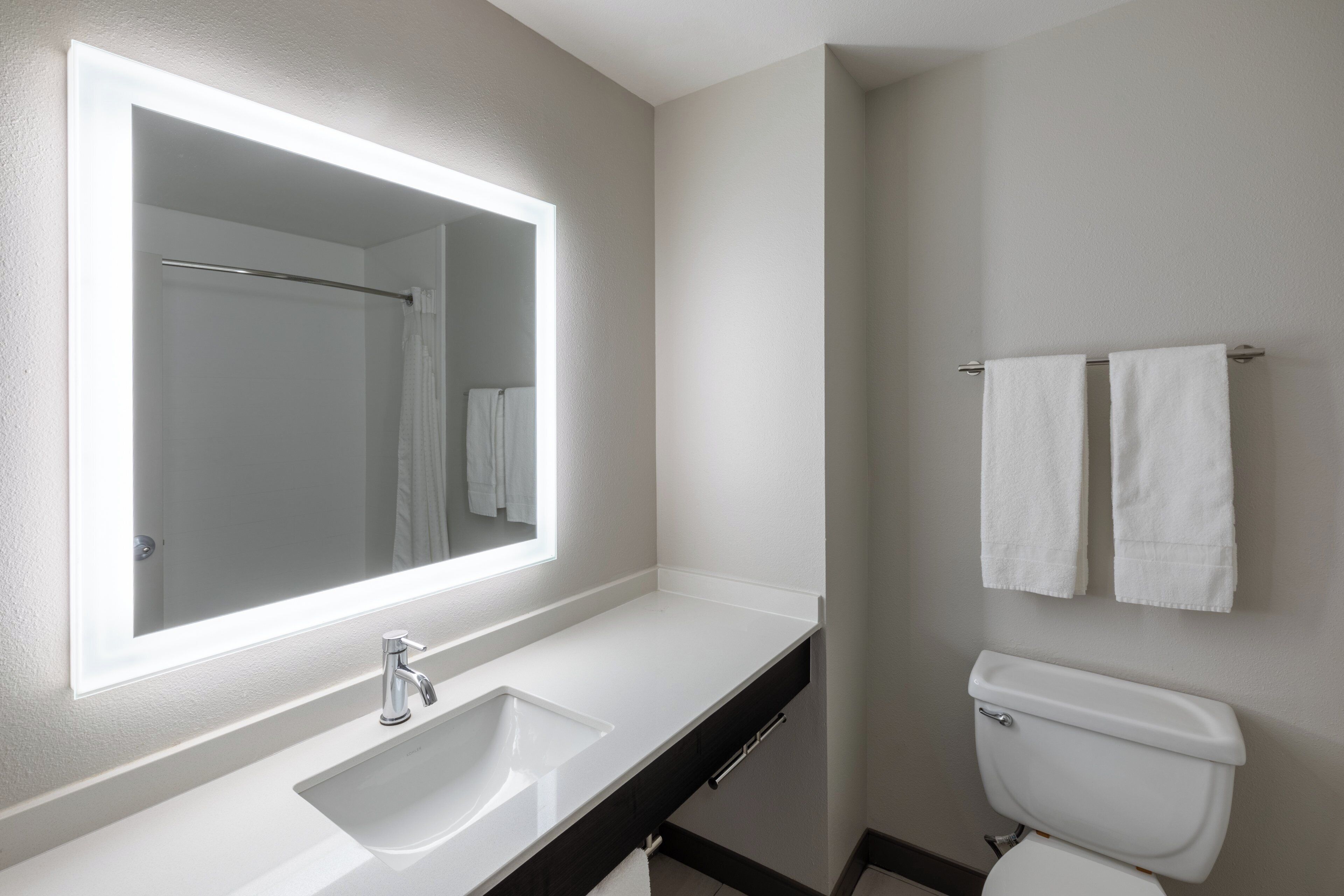 A bathroom with a white sink, a mirror, and a toilet.