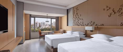 Habitación de hotel con dos camas, televisor, escritorio y vista a la ciudad.