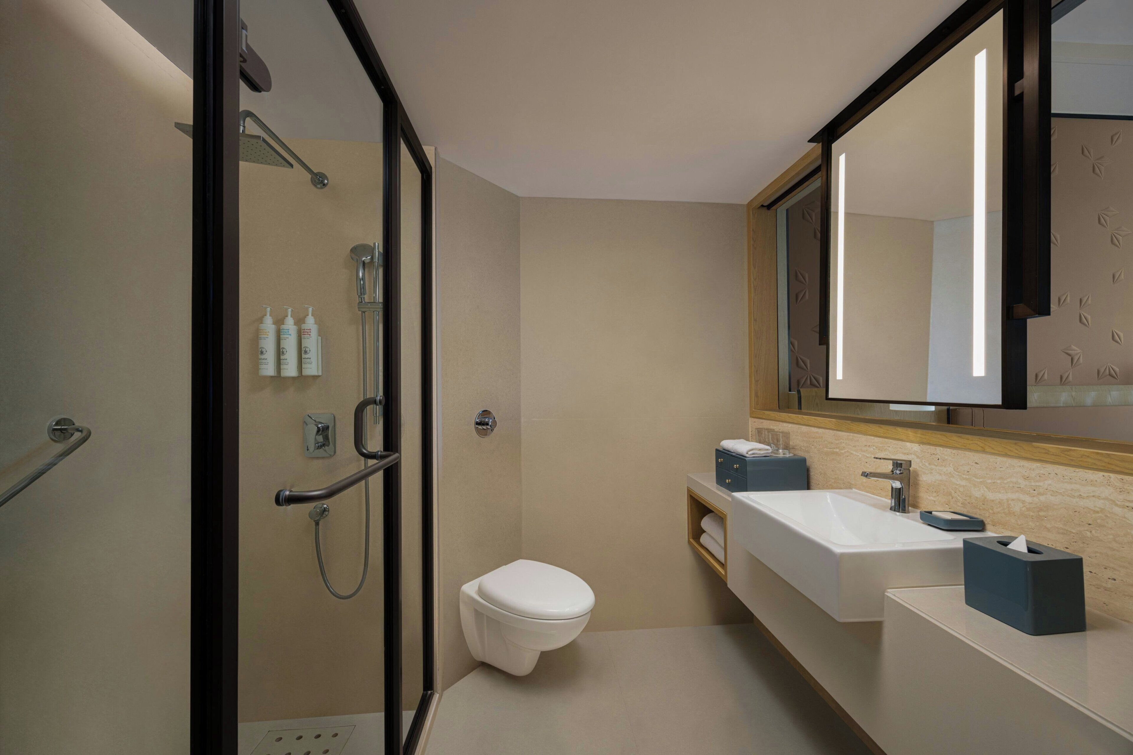 A modern bathroom with a shower, toilet, and sink.