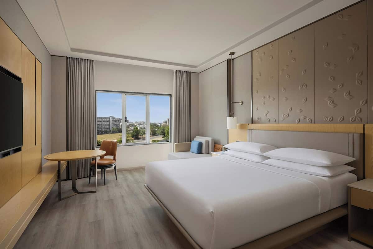 Quarto de hotel com cama, televisão, escrivaninha e cadeira.