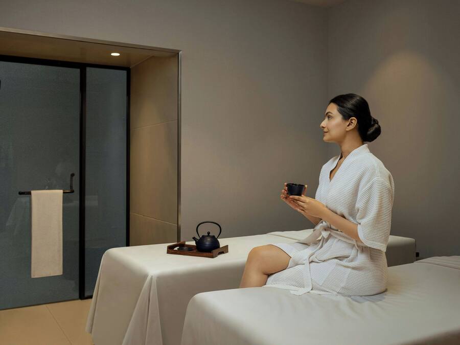 A spa room with a massage table, a tea set, and a towel rack.