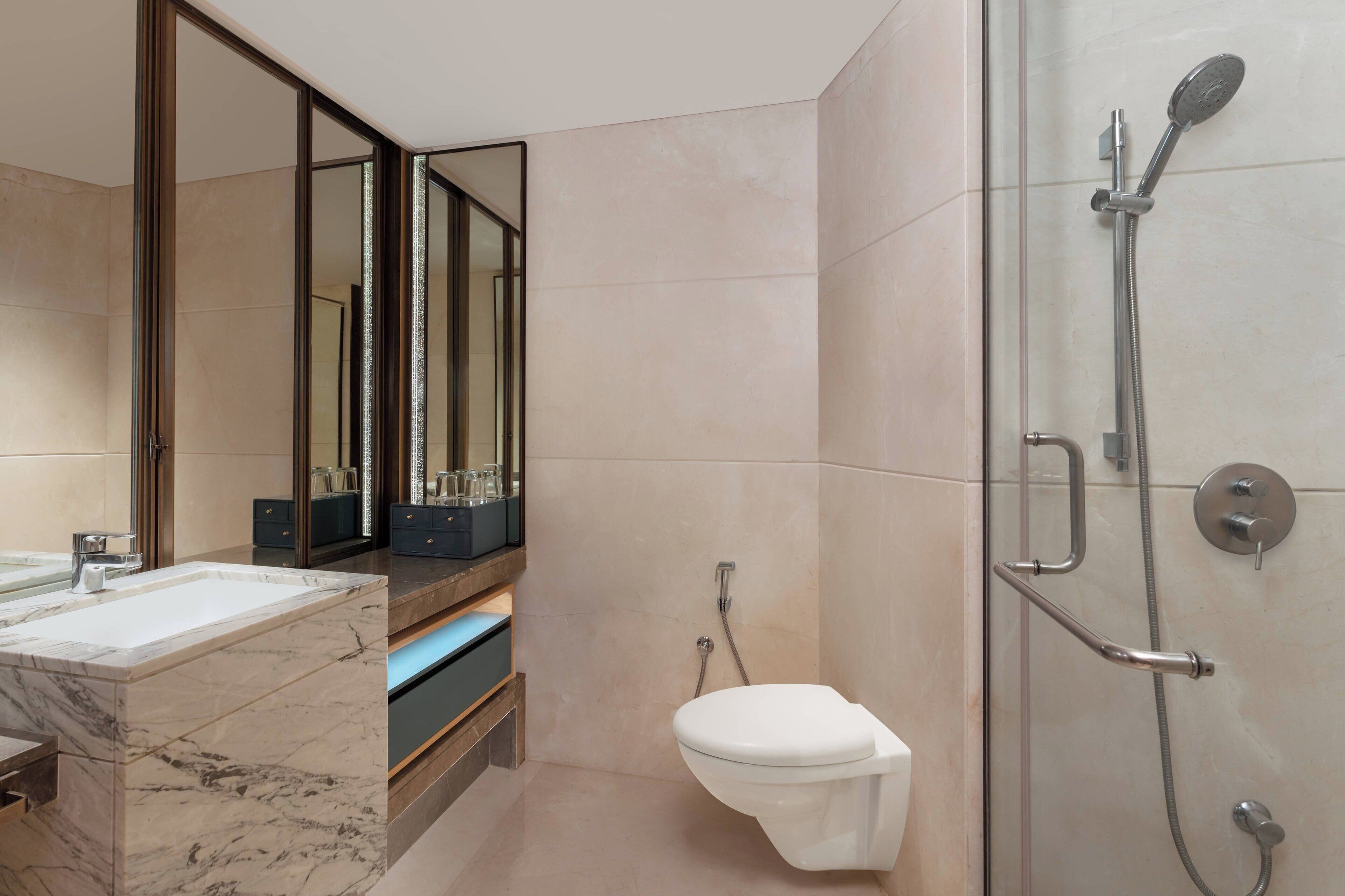 A modern bathroom with a marble sink, a glass-enclosed shower, and a toilet.