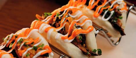 A row of food items, possibly tacos, with a sauce drizzled on top.