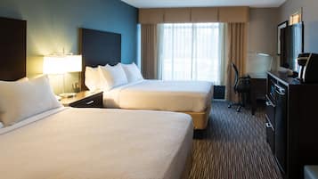 A hotel room with two beds, a desk, a television, and a minibar.