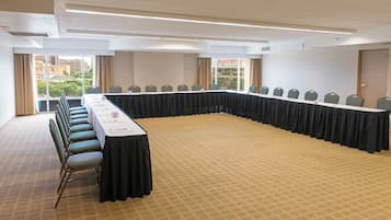 A conference room with a long table, chairs, and a carpeted floor.