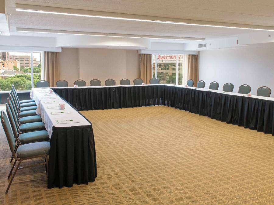 A conference room with a long table, chairs, and a carpeted floor.