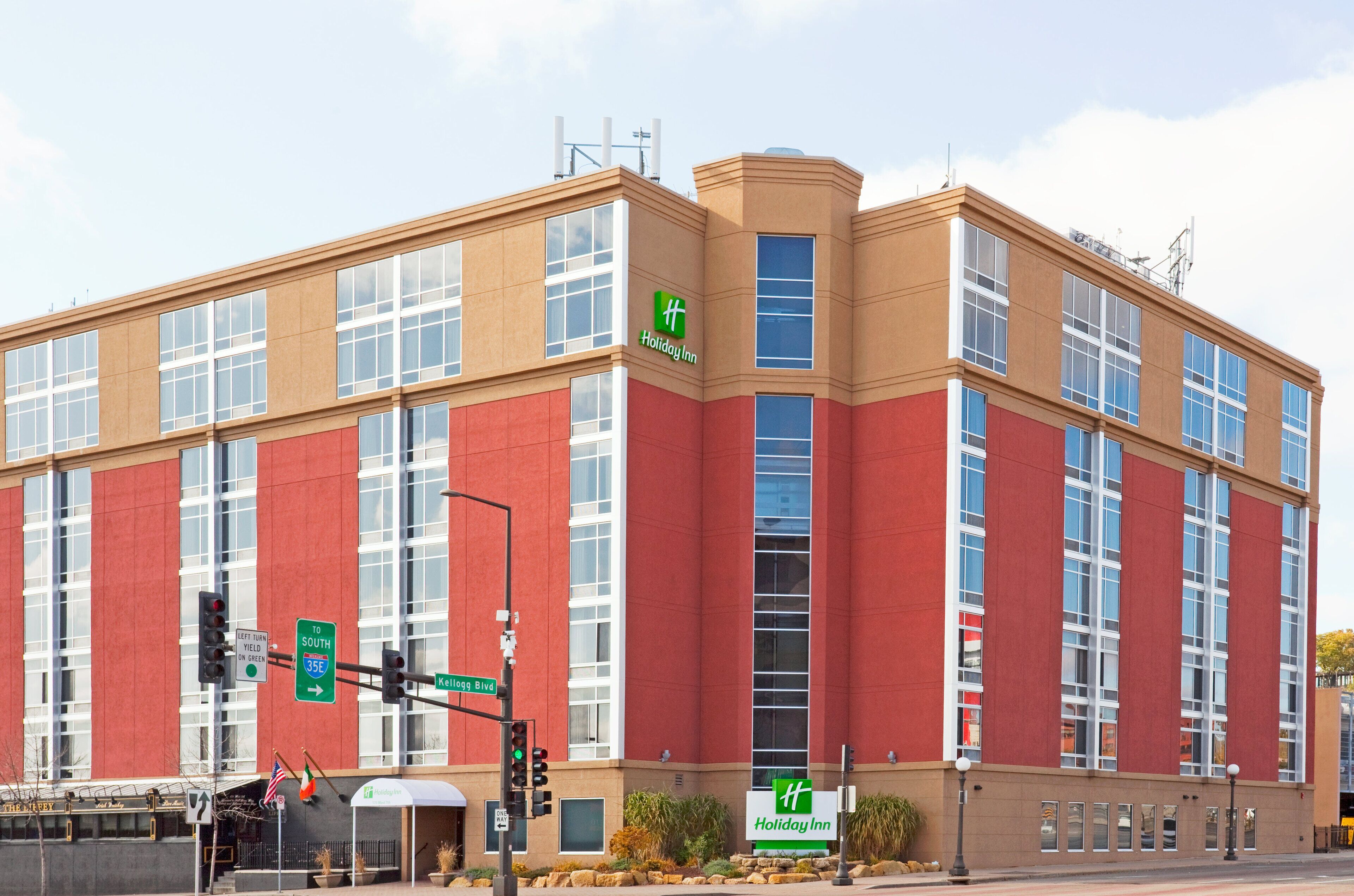 A Holiday Inn hotel with a red and beige facade, large windows, and a sign indicating the direction to South 35th Street.