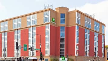 A Holiday Inn hotel with a red and beige facade, large windows, and a sign indicating the direction to South 35th Street.