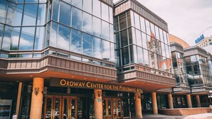 The exterior of the Ordway Center for the Performing Arts with large glass windows, a prominent entrance, and a brick facade.