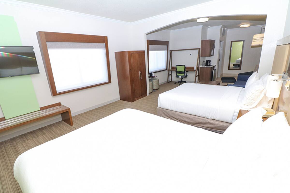 A hotel room with a large bed, a desk with a computer, a wardrobe, and a TV mounted on the wall.