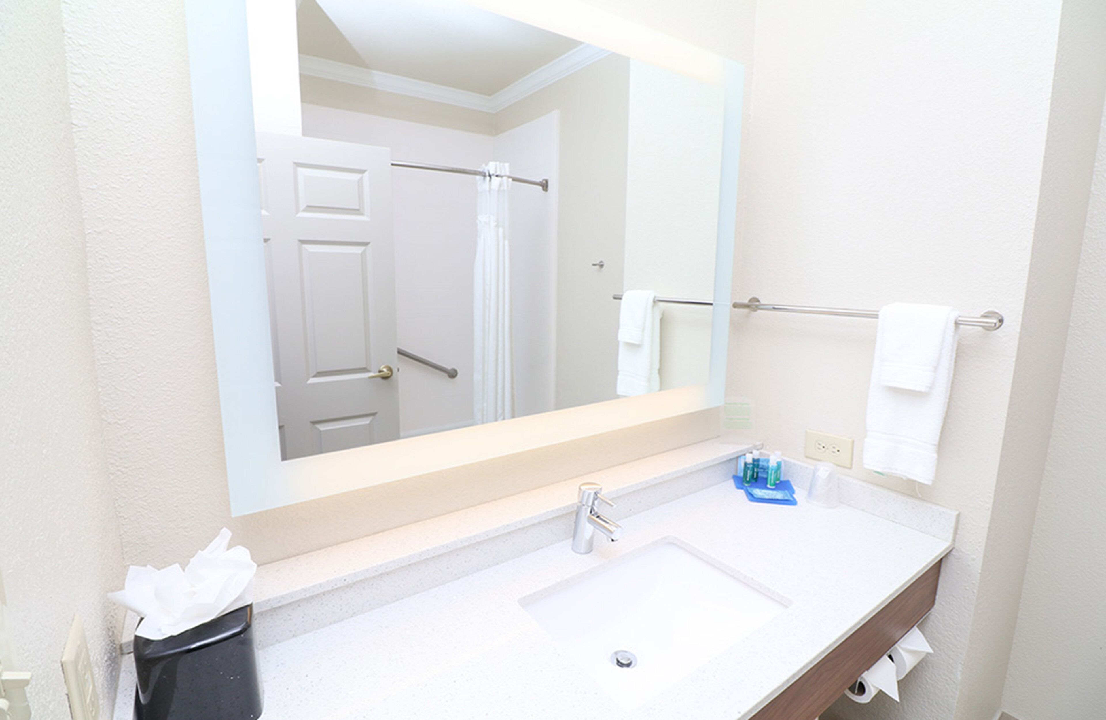 A bathroom with a white sink, a mirror, and a towel rack.