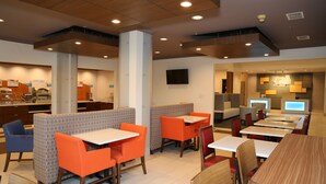 A modern restaurant with booths and tables, a counter, and a television. - Holiday Inn Express Hotel & Suites Greenville by IHG (Greenville)