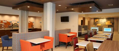 A modern restaurant with booths and tables, a counter, and a television.