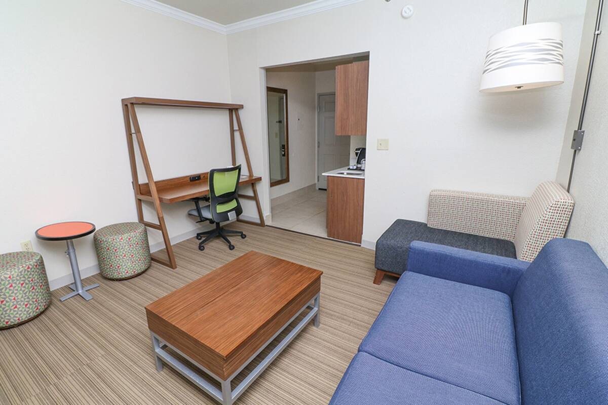 A compact living space with a sofa, a small table, a desk with a chair, and a kitchenette area.