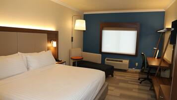 Habitación de hotel con una cama grande, un escritorio, una silla, una lámpara y una ventana.