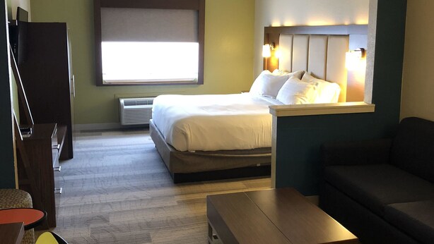 A hotel room with a bed, a sofa, a small table, a TV, and a window.