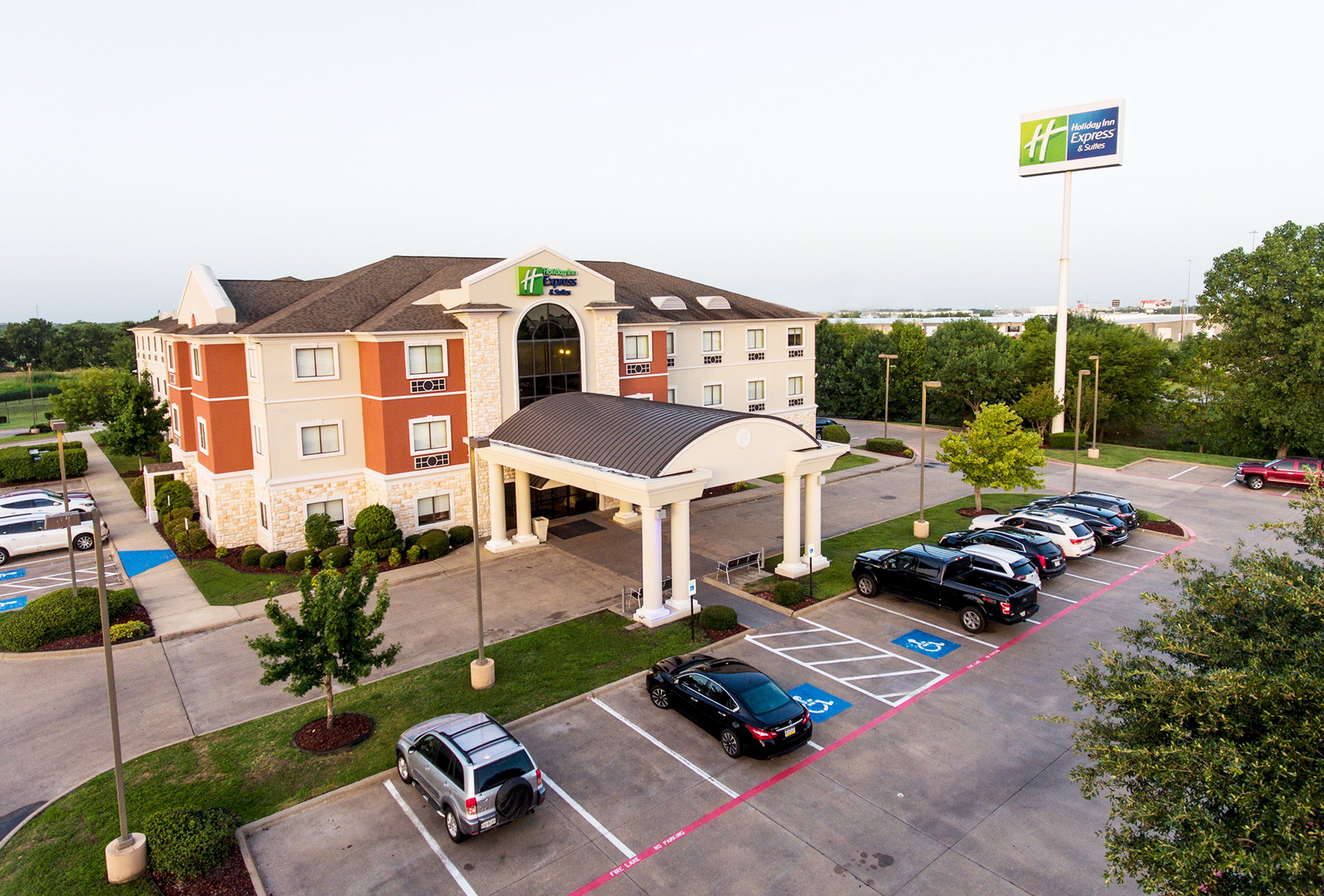 Un hôtel Holiday Inn Express & Suites doté d’un parking, d’une entrée couverte et d’une enseigne indiquant le nom de l’hôtel.