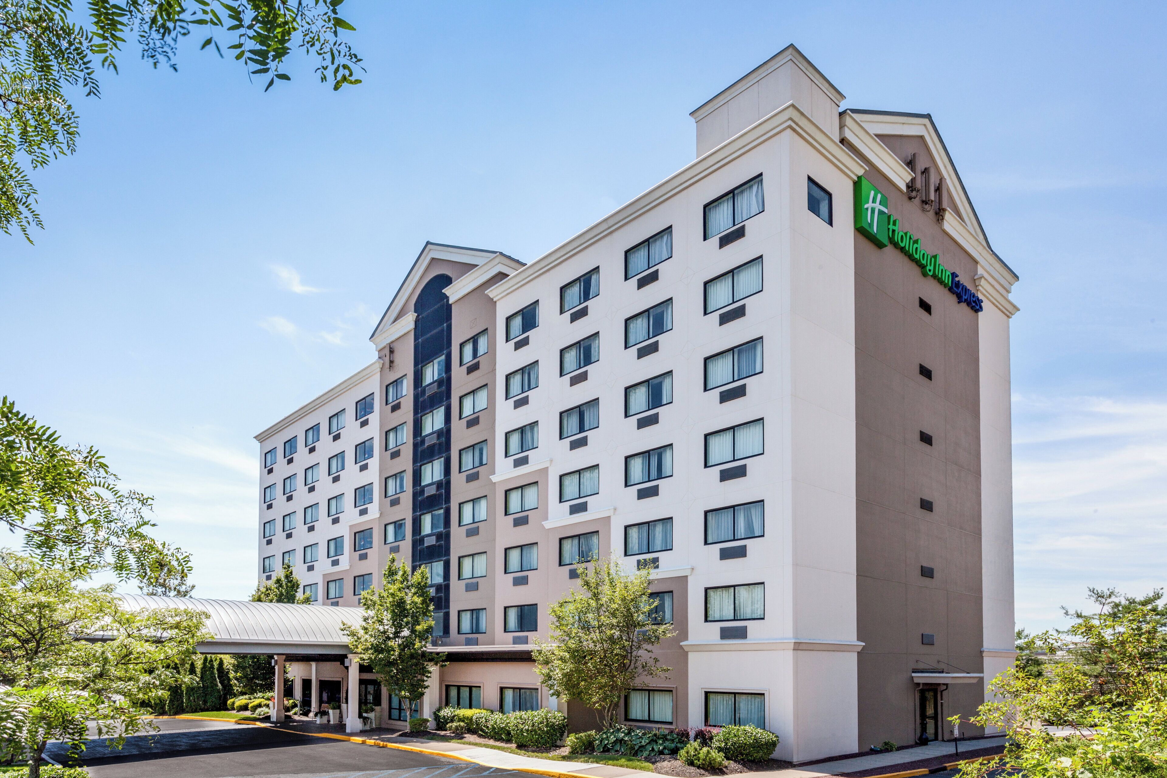 A multi-story hotel building with a flat facade, numerous windows, and a green sign indicating it is a Holiday Inn Express.