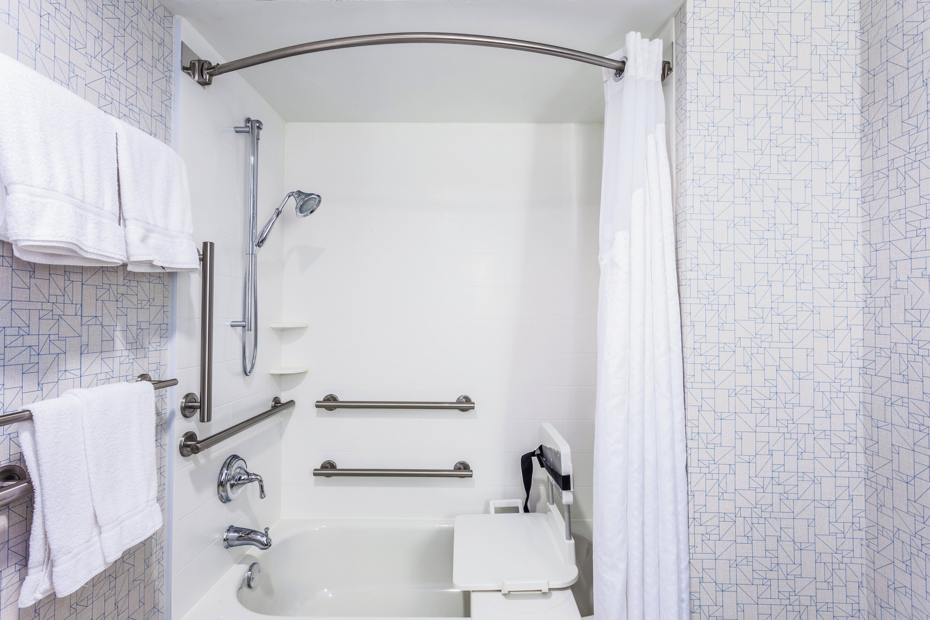A bathroom with a shower, grab bars, a towel rack, and a toilet.