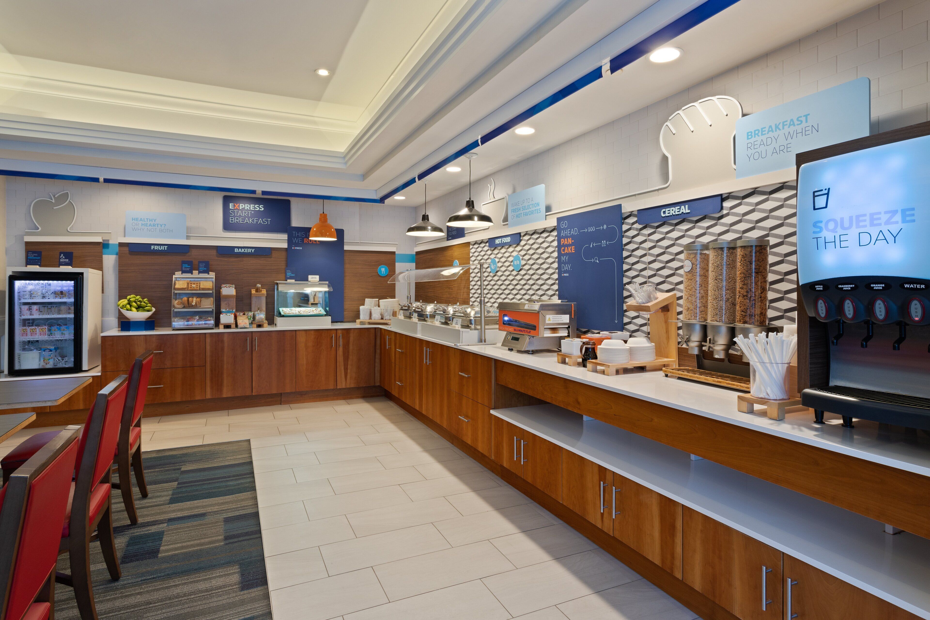 Uma área de café da manhã moderna com estação de autoatendimento, assentos e dispensador de água.