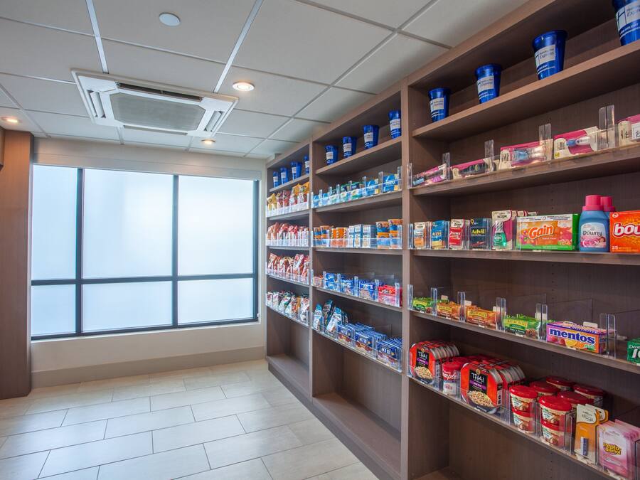 A grocery store with shelves stocked with various products and a large window providing natural light.