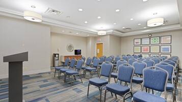 A conference room with rows of blue chairs, a podium, and a reception desk.