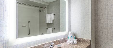 Un baño con un espejo grande, un lavamanos y una ducha.