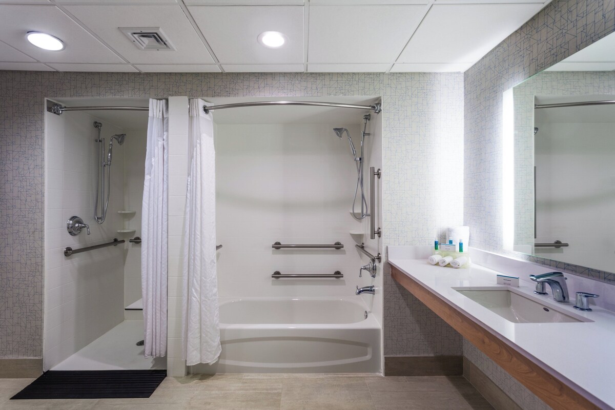 A modern bathroom with a walk-in shower, a bathtub, and a vanity with a sink and mirror.