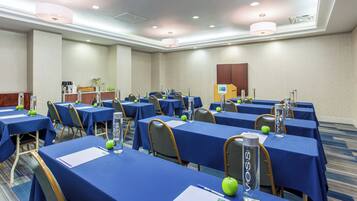 Un salón de conferencias con varias mesas, sillas y un atril.