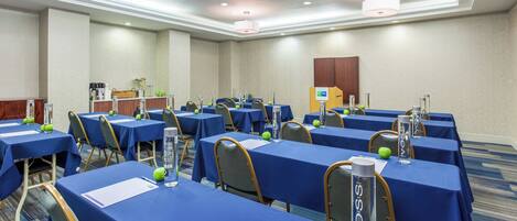 A conference room with multiple tables, chairs, and a podium.