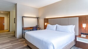 Habitación de hotel con una cama grande, un escritorio con silla, una lámpara de escritorio y una mesita de noche con teléfono.
