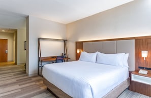 A hotel room with a large bed, a desk with a chair, a desk lamp, and a bedside table with a phone. -  Holiday Inn Express Hauppauge-Long Island (Hauppauge)