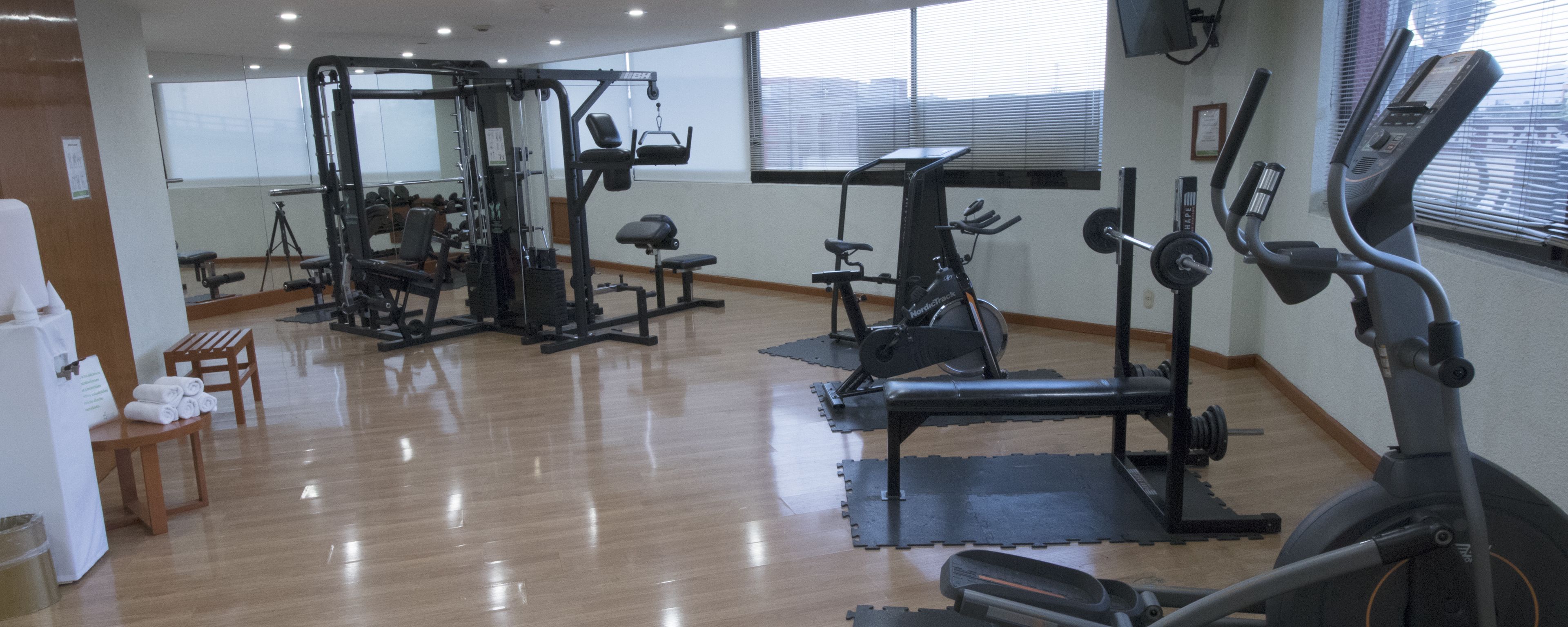 A gym with various exercise equipment, including a treadmill, weight machines, and a rowing machine.